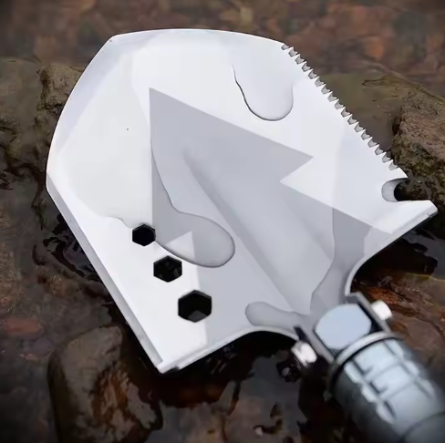Close-up of multi-tool shovel head with hex wrenches and saw edge resting on wet river rocks