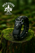 camo paracord survival bracelet with built-in compass resting on mossy tree stump in forest with Wild Living Company logo
