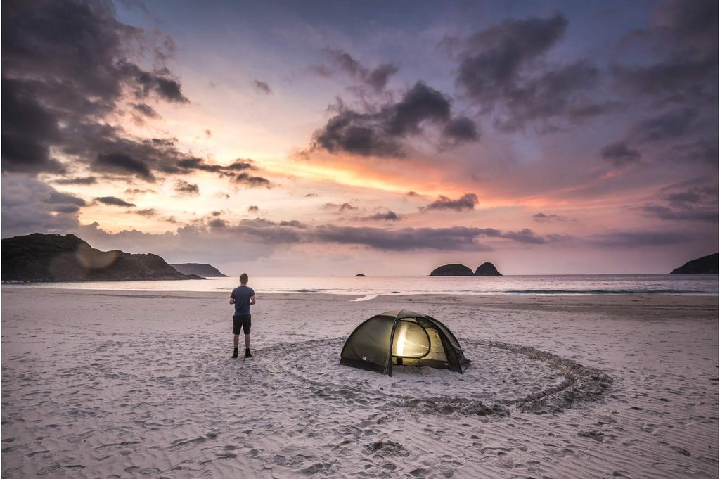 Fjällräven 53503 dome tent pitched at coastal campsite during sunset
