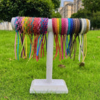 colourful mosquito repellent wristbands displayed on a white stand outdoors with grass and buildings in background


