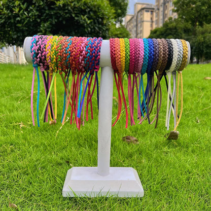 colourful mosquito repellent wristbands displayed on a white stand outdoors with grass and buildings in background

